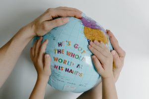 two sets of hands on a globe with the words "he's got the whole world in his hands" stickered on it