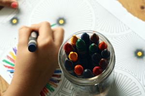 close up of kids hand coloring with crayons